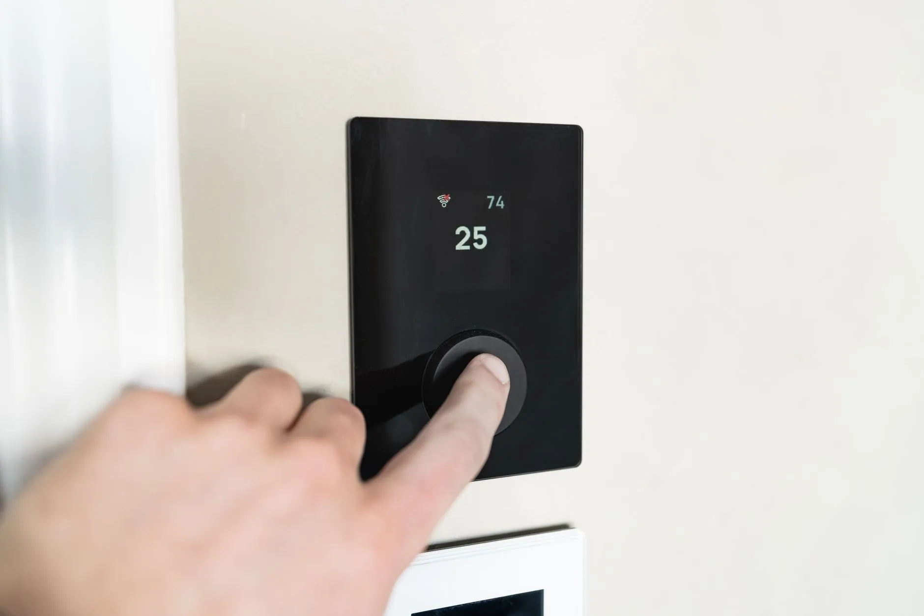 A hand adjusting a wall thermostat